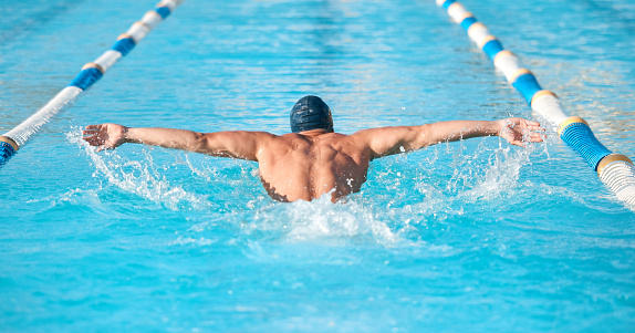 Shot of an unrecognizable young male athlete swimming in an olympic-sized pool