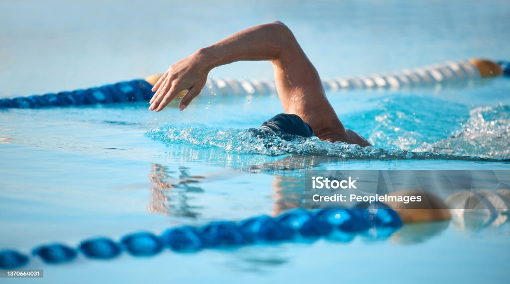 Shot of an unrecognizable young male athlete swimming in an olympic-sized pool Competing against himself Lap - Circuit Stock Photo