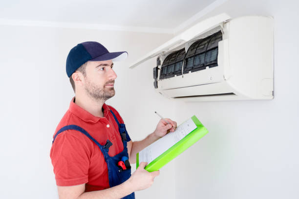 istock Technician with clipboard looking at air conditioner for installation quote 1370666967
