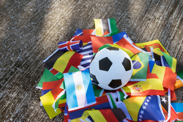 Ready for kick off leather soccer ball Above view of leather soccer ball on the ground with international team flags of the participating country in the championship tournament. Football equipment to play competitive game. Top-down international team soccer stock pictures, royalty-free photos & images