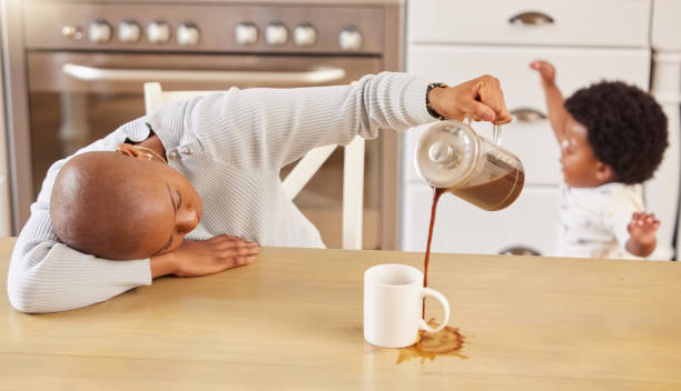 집에서 컵에 커피를 붓는 동안 자고있는 젊은 어머니의 샷 - people casual emotional stress table 뉴스 사진 이미지