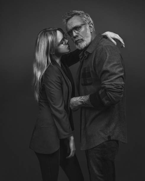 ritratto in bianco e nero di una coppia alla moda che indossa gli occhiali, in piedi di fronte a uno sfondo grigio - pair sensuality couple heterosexual couple foto e immagini stock