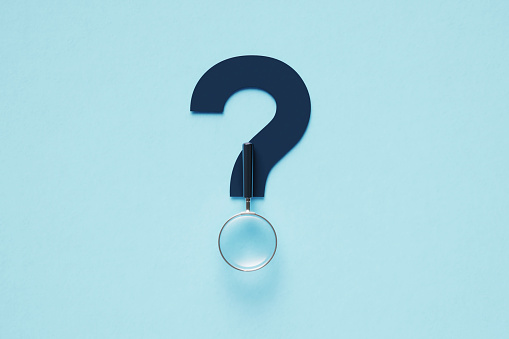 Magnifier forming a question mark on blue background. Horizontal composition with copy space.