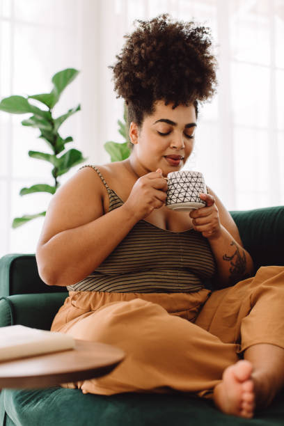 istock Woman sitting on couch having coffee 1370671225