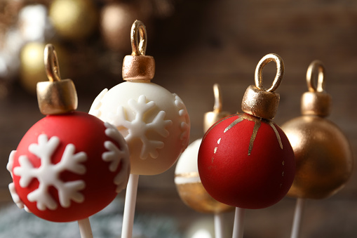 Delicious Christmas ball cake pops on blurred background, closeup