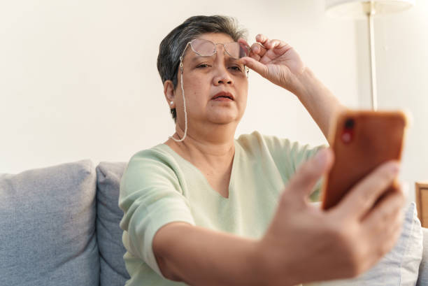 istock Senior Asian woman with presbyopia, taking off eyeglasses while reading message from smart phone. 1370671536