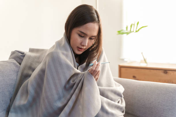 istock Young Asian woman measuring her temperature with a thermometer. 1370672082