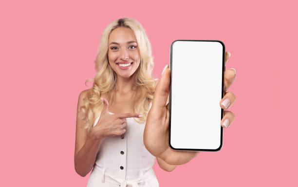 istock Smiling blonde woman pointing at white empty smartphone screen 1370672130