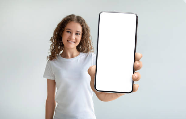 istock Pretty curly young woman holding smartphone with empty screen 1370672281
