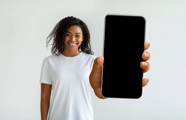 istock Pretty african american woman holding smartphone with empty screen 1370672723