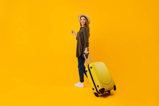istock Tourist Lady Standing With Suitcase Posing Over Yellow Studio Background 1370673142