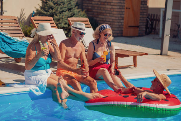 istock Senior people drinking cocktails and relaxing by the pool 1370673583