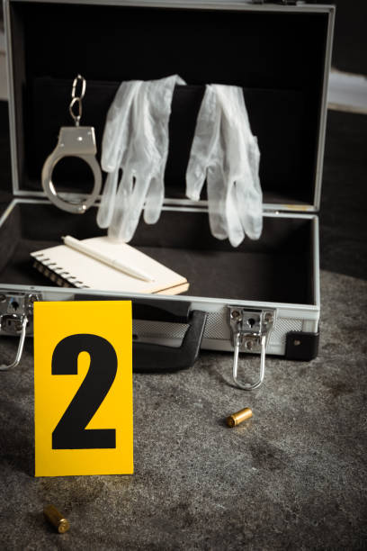 istock Crime scene marker and open case with police equipment on grey stone table 1370673707