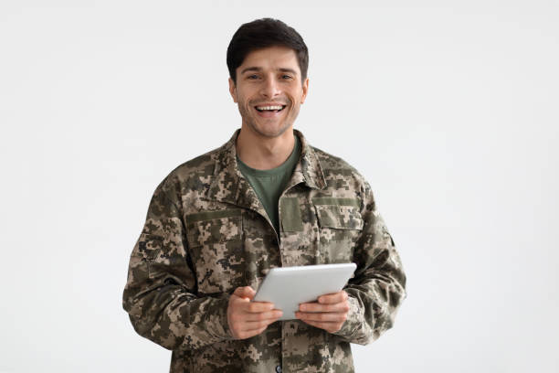 Smiling man in camouflage uniform holding digital tablet