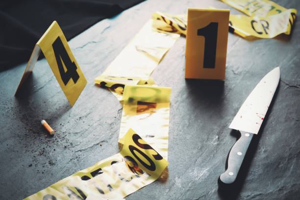 evidence markers, yellow tape and knife on black slate table. crime scene - csi imagens e fotografias de stock
