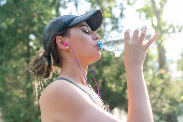 istock Healthy female sitting outdoors and drinking water after exercising session. 1370674441