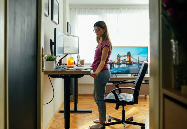 istock Woman working at standing desk adjusting the height 1370674681
