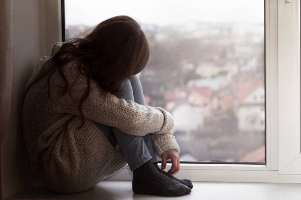 istock Depressed Teen sitting alone by window. 1370676309