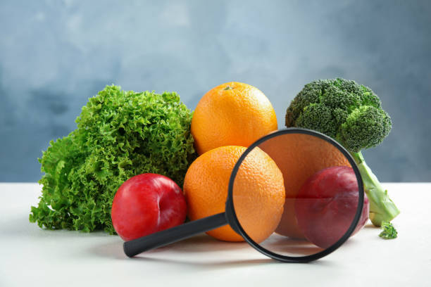 istock Fresh fruits, vegetables and magnifying glass on white table against light blue background. Food poisoning concept 1370677613