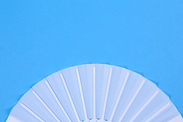 istock White hand fan on light blue background, top view. Space for text 1370678586