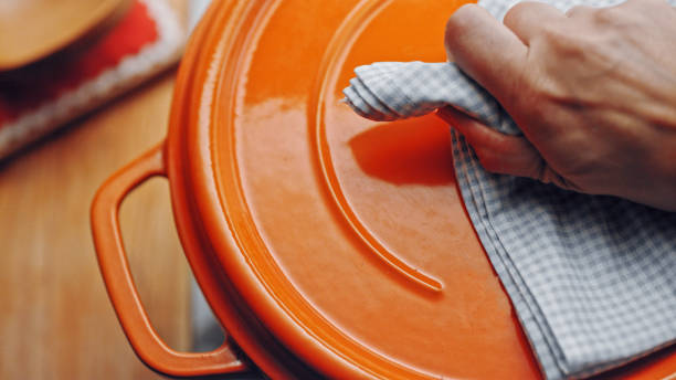 オレンジの鍋のふた�を持つ手のトップショット。 - pan saucepan kitchen utensil isolated ストックフォトと画像
