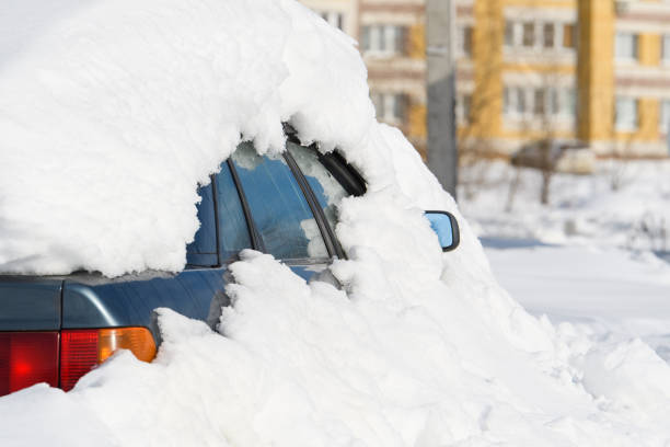 A frozen car on the parking completely covered in a thick layer of glistening snow
