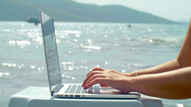 istock Women use a green screen computer on the beach. 1370682796