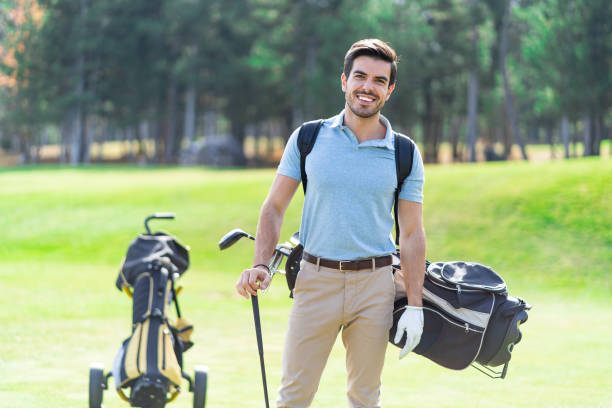 istock Smiling golf player standing on a golf course with a    backpack on his back and holding a golf club in his hand 1370683567