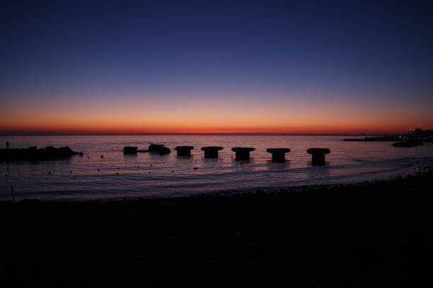 Sunset over the seashore with concrete embankment and small pier