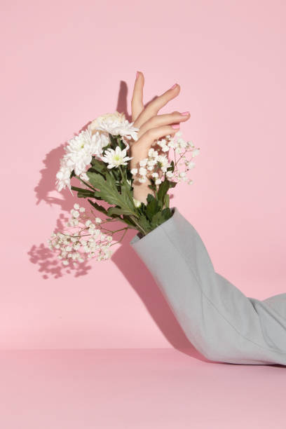 istock Spring creative layout with flowers and hand in jacket sleeve against pastel pink background. Romantic fashion aesthetic concept. Minimal bloom idea. 1370686268