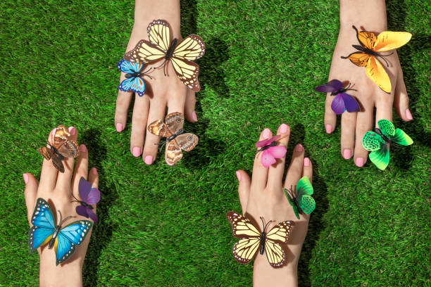 istock Spring creative layout with multi colored butterflies on hands against bright green grass background. Romantic fashion aesthetic concept. Minimal summer idea. 1370686893