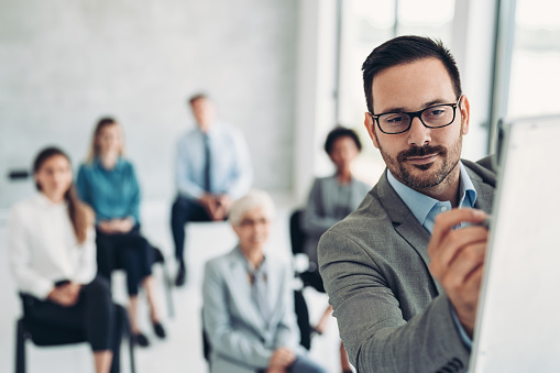 Focus on the face of a businessman writing on a flipchart during a business educational event