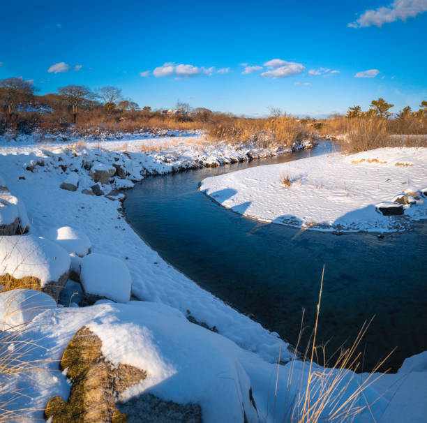 Snow over the curving riverbank in Falmouth Height on Cape Cod, Massachusetts.