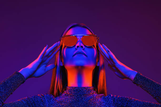 Neon close up portrait of young woman in red sunglasses. Studio shot stock photo