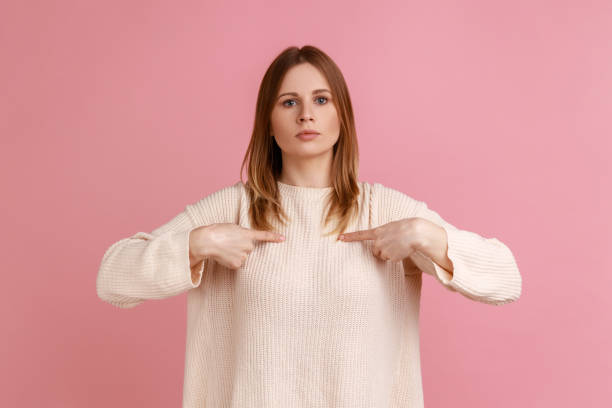 mujer señalándose a sí misma y mirándose con arrogancia a la cámara, siendo orgullosa y egoísta. - smug fotografías e imágenes de stock