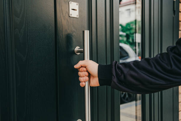 man hand opens a wooden door . pulls on a metal aluminum handle