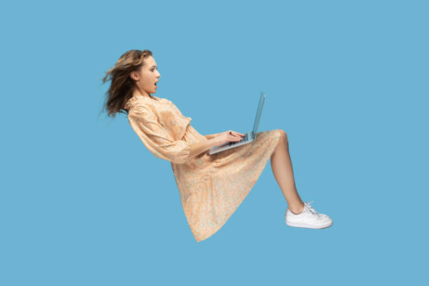 Surprised girl levitating, looking at laptop screen shocked amazed, stock photo