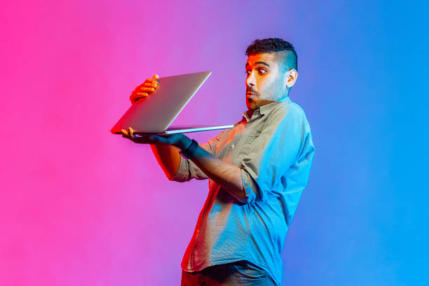 istock Man holding laptop in hands, sees shocking scared content, looking at display with big eyes. 1370692016