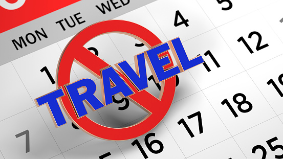 Banned sign and travel text. On white-colored calendar page. Horizontal composition with copy space. Focused image.