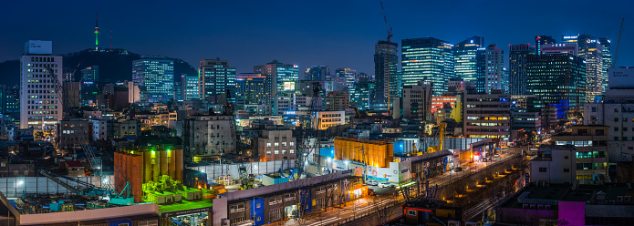 The iconic spire of the N Seoul Tower high on Namsan Mountain overlooking the crowded neon cityscape of central Seoul at night, South Korea.