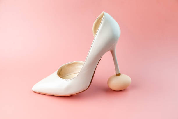 istock A woman's white shoe stands with a heel on a chicken egg. Concept photo. 1370694198