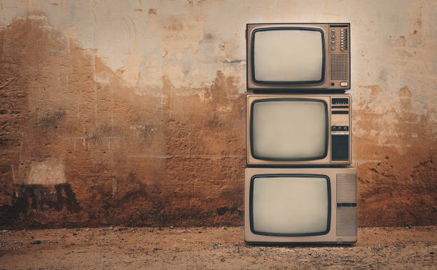 televisores antigos e velhos se acumulam no chão em frente ao fundo da parede velha. foto estilo vintage, três tvs antigas com espaço de cópia à esquerda - three objects audio - fotografias e filmes do acervo