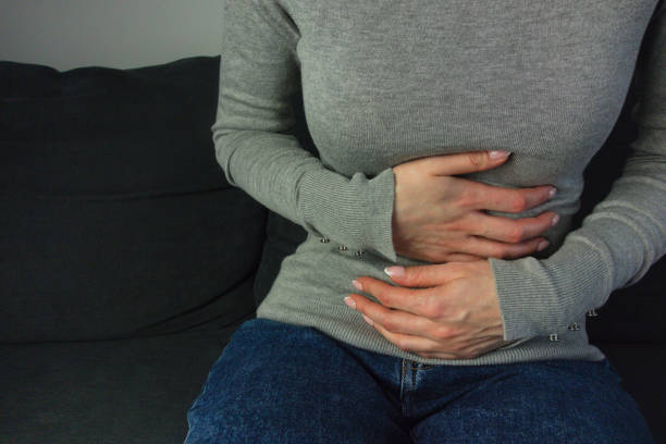 kobieta cierpiąca na ból brzucha siedząca na kanapie - peptic ulcer zdjęcia i obrazy z banku zdjęć