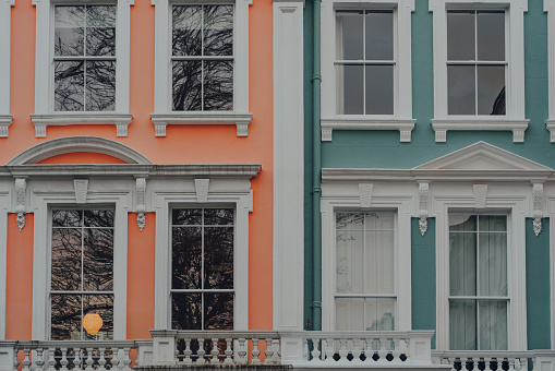 Close up of orange and turquoise pastel coloured terraced houses in Primrose Hill, North London, UK.