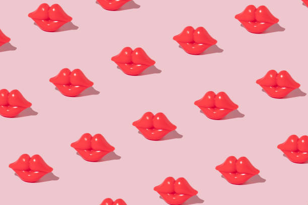 パステルピンクの背景に真っ赤な唇のフィギュアで作られた創造的なパターン。ロマンチックなレトロなスタイルのアイデア。バレンタインデーのコンセプト - lipstick kiss kissing lipstick love ストックフォトと画像
