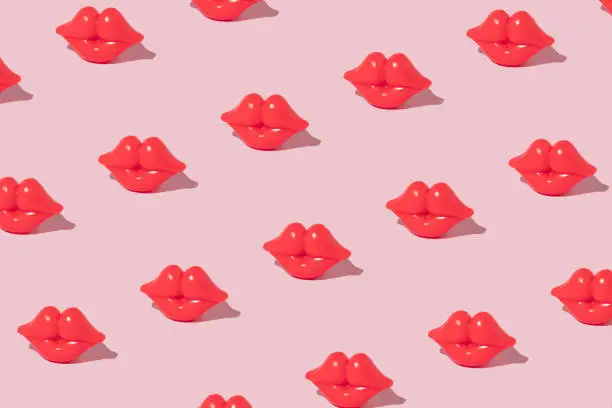 Photo of Creative pattern made with bright red lips figurine on pastel pink background. Romantic retro style idea. Valentine day concept