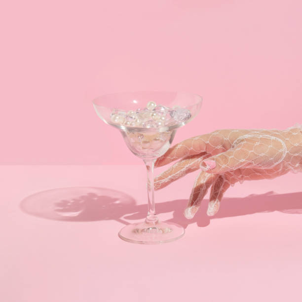 파스텔 핑크 배경에 다이아몬드와 진주가 있는 화이트 레이스 글러브 래칭 마티니 칵테일 글래스를 손에 넣은 창의적인 레이아웃. 80 년대 또는 90 년대 복고풍 미적 패션 컨셉. 로맨틱 한 음료 � - lace gloves 뉴스 사진 이미지