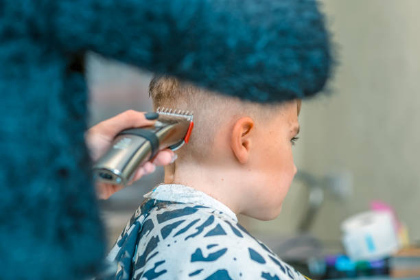 Side view of happy boy is sitting in barber salon with wet hair and cuts her hair. Side view Happy boy is sitting in barber salon with wet hair and cuts her hair. Combing stock pictures, royalty-free photos & images