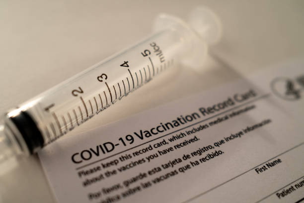 istock Covid-19 Vaccination Card with a Plastic Syringe on White Background 1370699520