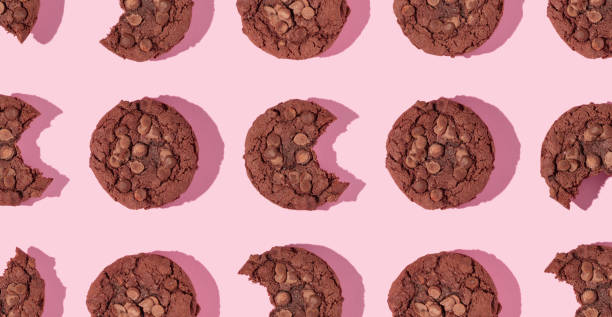 Creative pattern made with chocolate chip cookies on pastel pink background. Happy sweet optimistic life idea. Fun food or dessert concept. Spring or summer layout.